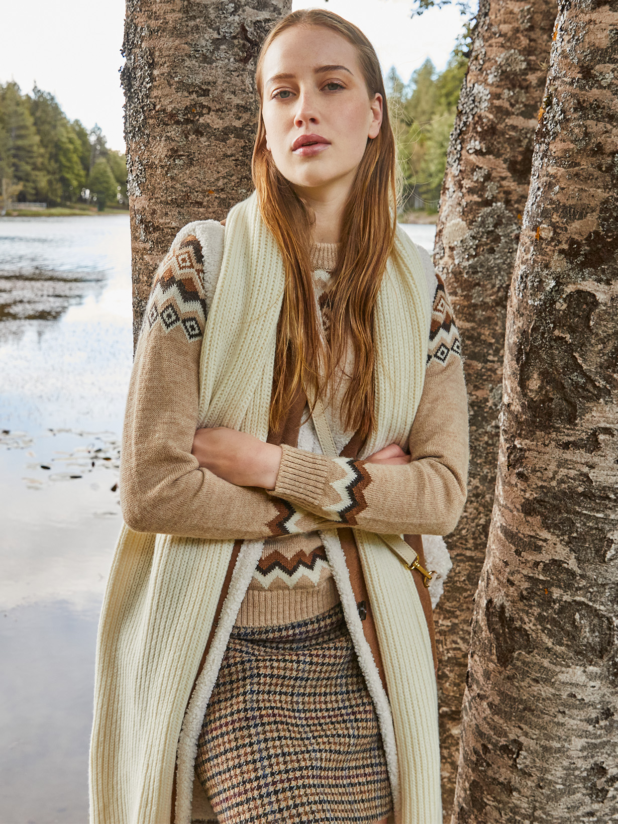 Modella indossa maglione con decorazioni e sciarpa bianca.