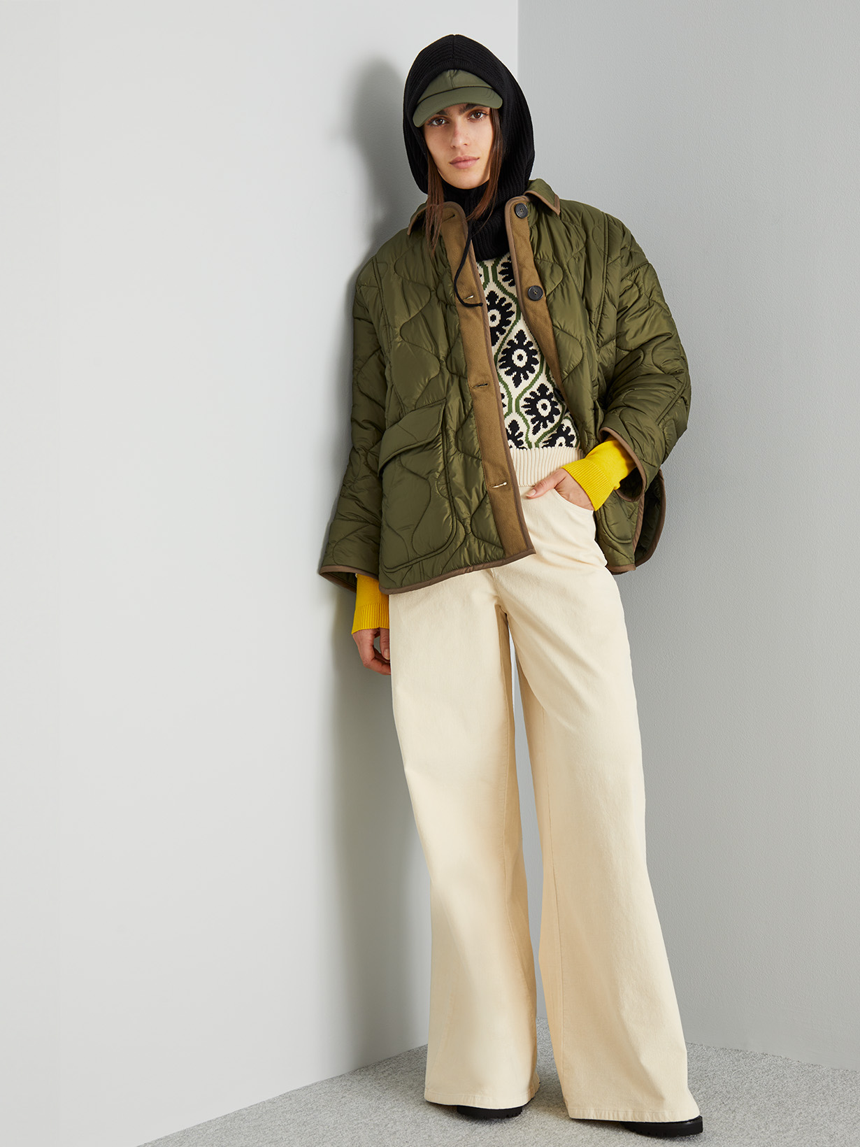 Modella indossa imbottito verde e pantaloni beige.